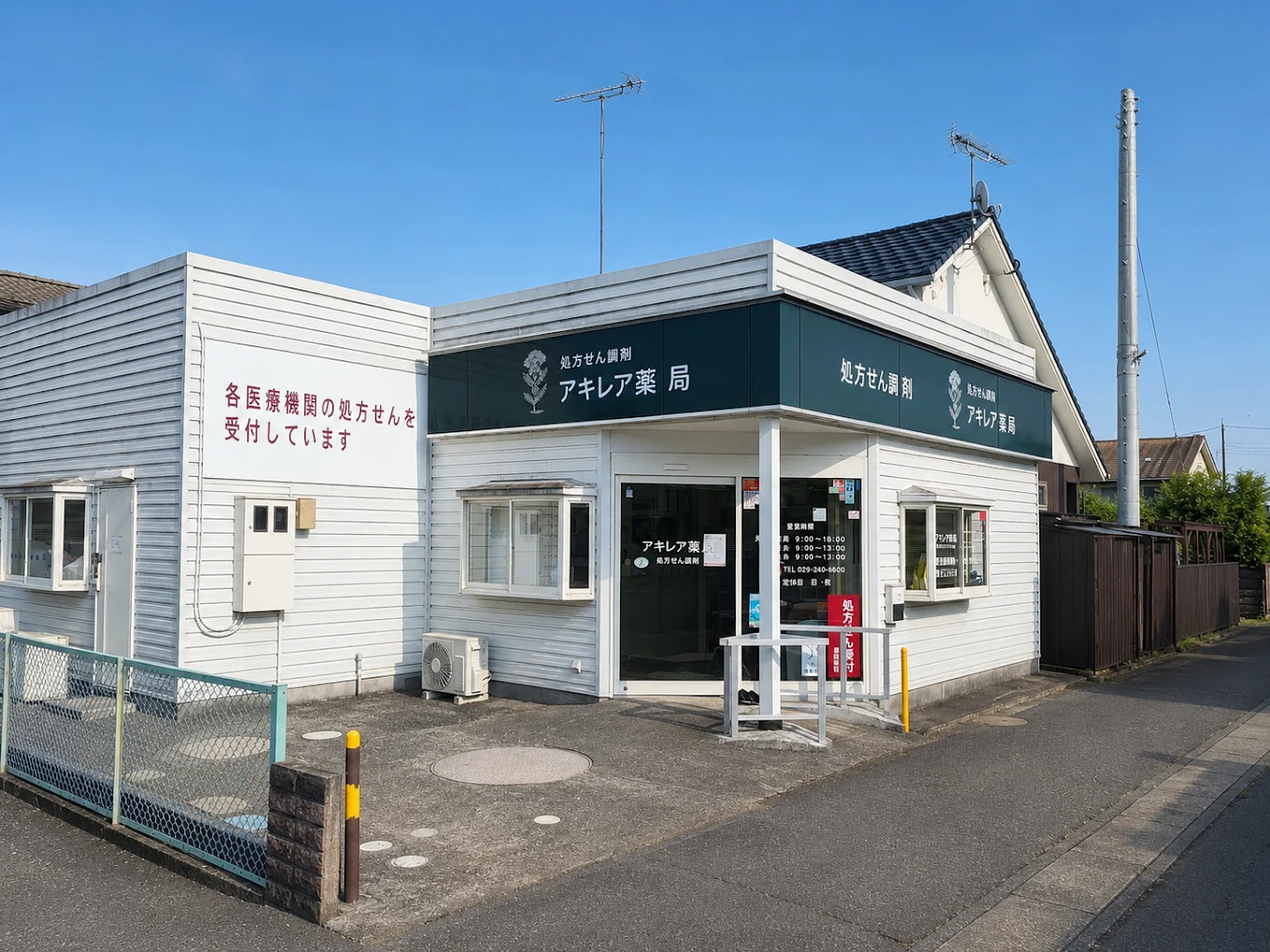白い外壁と深い緑の看板が目印のアキレア薬局